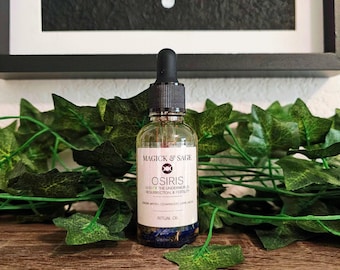 May include: A clear glass dropper bottle containing ritual oil with a black dropper cap. The white label features the text Magick & Sage, Osiris, God of the Underworld, Resurrection & Fertility, and lists Cassia, Myrrh, Cedarwood, and Lapis Lazuli.