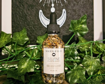 Könnte beinhalten: Eine klare Glastropfflasche gefüllt mit botanischem Öl, getrockneten Blumen und kleinen Kristallen. Das weiße Etikett trägt die Aufschrift MAGICK & SAGE, SELENE GODDESS OF THE MOON, JASMINE, CLARY SAGE, CHAMOMILE, QUARTZ, RAINBOW MOONSTONE, RITUAL OIL.