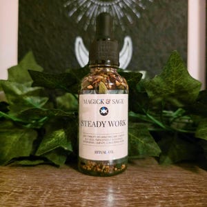May include: A clear glass dropper bottle containing oil and botanical herbs. The white label reads MAGICK & SAGE, STEADY WORK, RITUAL OIL, and lists benefits including stability, reliable income, career success, employment blessings, and clients.