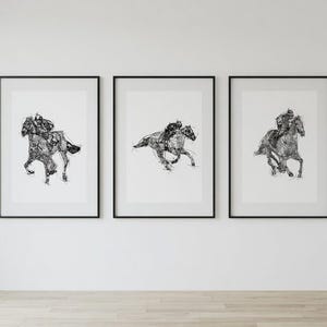 May include: Three framed black and white art prints of racehorses and jockeys. Each print features a detailed sketch of a horse in motion, with a jockey riding. The prints are displayed on a white wall.