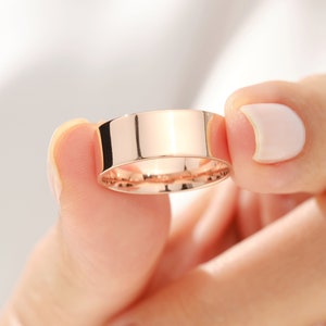 May include: A simple, polished, rose gold wedding band.