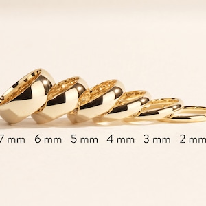 K&ouml;nnte beinhalten: Ein Satz von sechs goldenen Ringen, jeder mit einer anderen Breite, von 2 mm bis 7 mm. Die Ringe sind nach Gr&ouml;&szlig;e geordnet, der gr&ouml;&szlig;te Ring links und der kleinste Ring rechts.