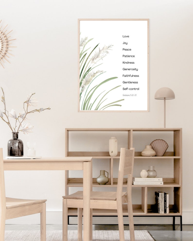 K&ouml;nnte beinhalten: Ein gerahmter Druck mit einer Aquarell-Illustration von gr&uuml;nem Gras und wei&szlig;en Blumen. Der Druck zeigt eine Liste von Tugenden: Liebe, Freude, Friede, Geduld, Freundlichkeit, Gro&szlig;z&uuml;gigkeit, Treue, Sanftmut und Selbstbeherrschung. Der Text "Galater 5,22-25" ist unten auf dem Druck gedruckt.