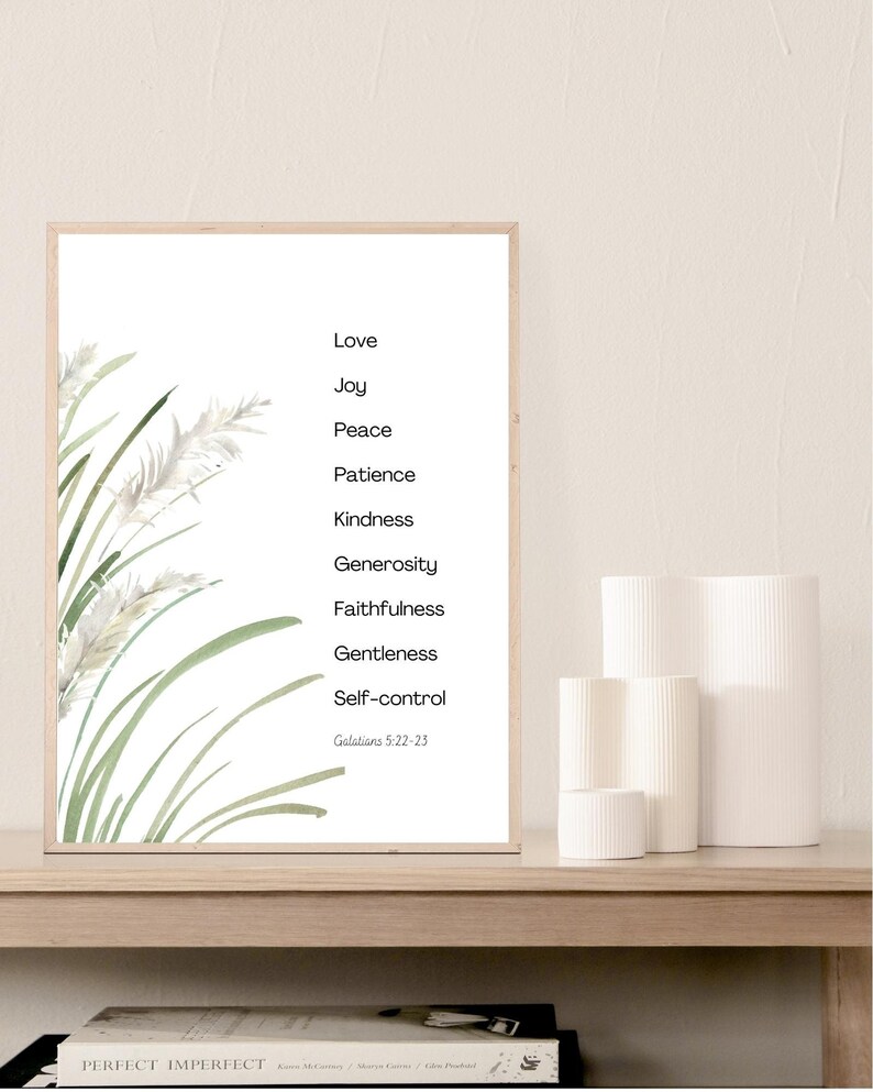 K&ouml;nnte beinhalten: Ein wei&szlig; gerahmter Druck mit einer Aquarell-Illustration von gr&uuml;nem Gras und wei&szlig;en Blumen. Der Druck zeigt eine Liste von Tugenden: Liebe, Freude, Friede, Geduld, Freundlichkeit, Gro&szlig;z&uuml;gigkeit, Treue, Sanftmut, Selbstbeherrschung. Der Text "Galater 5:22-23" befindet sich am unteren Rand des Drucks.