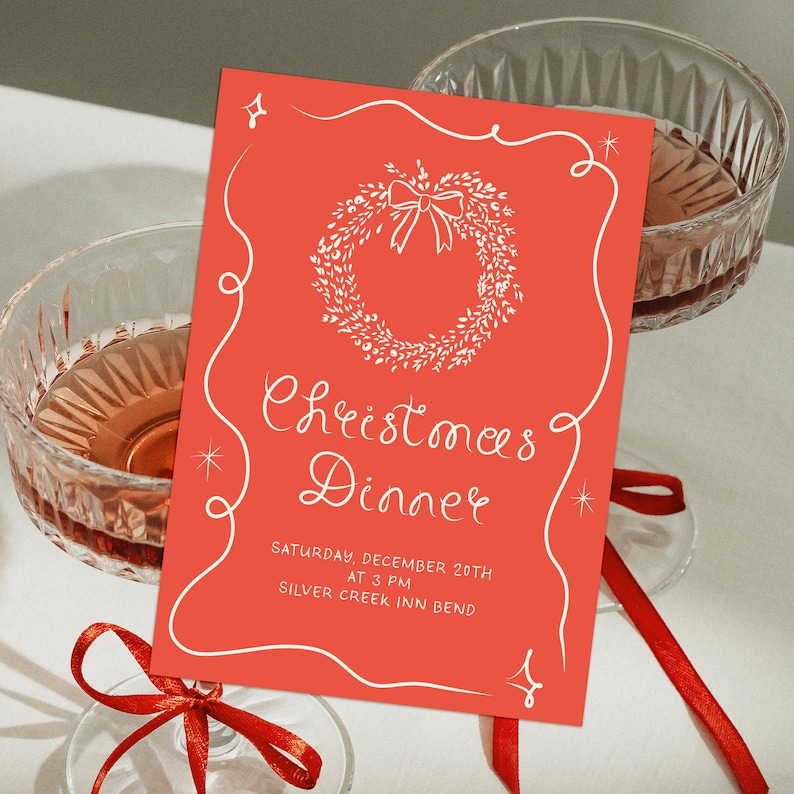 May include: A red invitation card with a white wreath and bow design. The text reads "Christmas Dinner" with the date and time "Saturday, December 20th at 3 PM" and the location "Silver Creek Inn Bend".