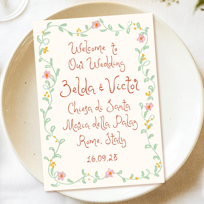 May include: A wedding invitation with a floral border. The text reads "Welcome to Our Wedding Zelda & Victor Chiesa di Santa Maria della Palaz Rome, Italy 16.09.25".