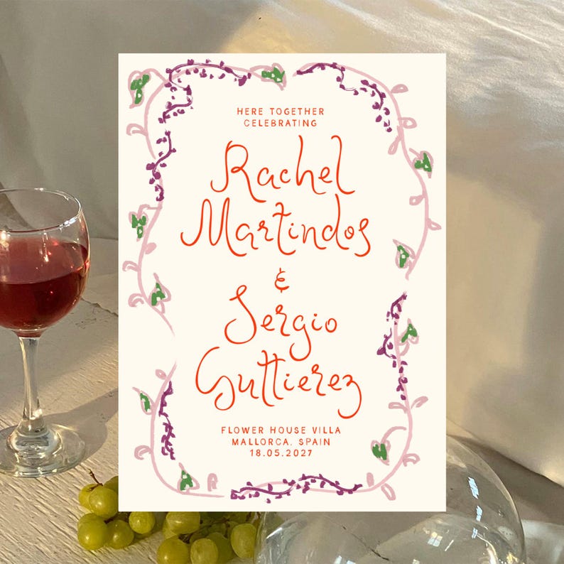 May include: A wedding invitation with a floral border in shades of pink, purple, and green. The text reads "Here together celebrating Rachel Martinos & Sergio Gutierrez Flower House Villa Mallorca, Spain 18.05.2027"
