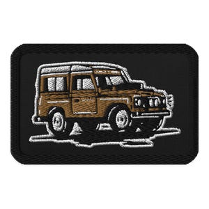 May include: Embroidered patch depicting a brown vintage off-road vehicle with a white roof and outline. The patch is rectangular with a black background and a white border. The vehicle has detailed stitching.