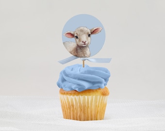Puede incluir: Un cupcake azul con glaseado blanco en espiral coronado con un adorno redondo que representa un cordero.