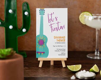 Op de afbeelding: Een kleurrijke uitnodiging met een turquoise gitaarillustratie en de tekst "Let's Fiesta!" Savannah Turner wordt zeven jaar op 1 mei 2023 van 13:00 tot 15:00 uur. De uitnodiging bevat het adres 36 Vermont Drive, Clarksville, TN 37040 en een RSVP-nummer 126-555-8345.