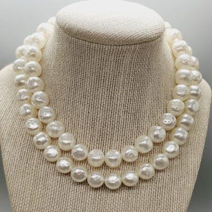 May include: A double strand pearl necklace with large, white, round pearls. The necklace is displayed on a white mannequin.