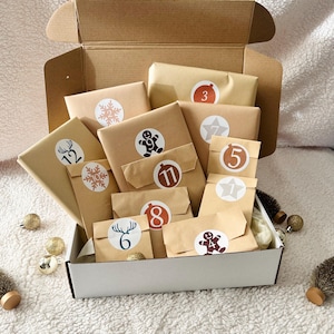 May include: A white box filled with brown paper packages, each with a different number and design. The box is open and the packages are visible. The packages are decorated with snowflakes, stars, gingerbread men, and reindeer.