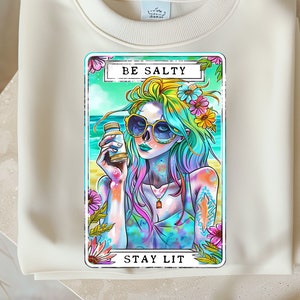 May include: A colorful illustration of a woman with blue hair and sunglasses holding a bottle of liquid. The illustration is on a card with the text "BE SALTY" and "STAY LIT".