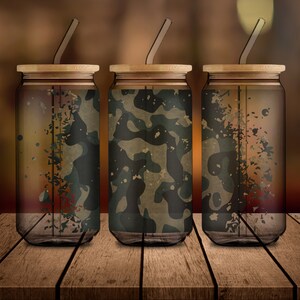 May include: Three clear glass tumblers with wooden lids and straws. Each tumbler has a different camouflage pattern printed on the outside.