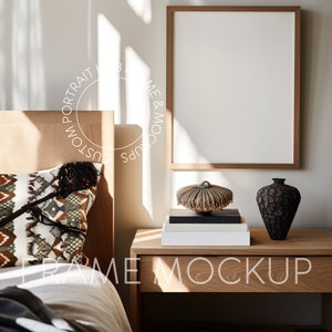 May include: A wooden bed frame with a white bedspread and a patterned pillow. A wooden nightstand with a white book, a decorative object, and a black vase with a patterned design. A framed picture with a white background hangs on the wall.