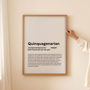 May include: A framed print with the word "Quinquagenarian" and its definition. The text is black on a white background, with a light brown wooden frame. The definition includes a humorous description.