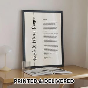 May include: A framed wall art print featuring the text Baseball Mom's Prayer in a vertical black script font on a cream background. The prayer text is printed in a smaller black serif font. The frame is black and rectangular in shape.