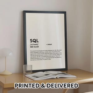 May include: A black framed print featuring the word "SQL" and its definition. The print is on a light-coloured desk with an open book and a glass. The text "PRINTED & DELIVERED" is at the bottom of the image.