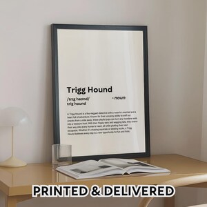 May include: A framed print with the text "Trigg Hound" in a black frame. The print includes a definition of a Trigg Hound, describing it as a four-legged detective. The phrase "PRINTED & DELIVERED" is at the bottom.