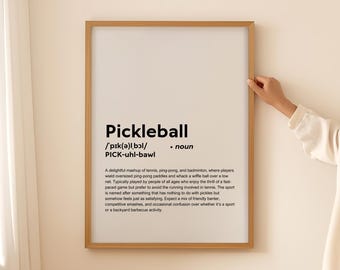 Puede incluir: Una impresión enmarcada con fondo blanco y texto negro que define la palabra "Pickleball". El texto incluye la pronunciación y una definición del deporte.