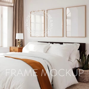 May include: A white bed with a brown throw blanket and white pillows. Three wooden picture frames are hanging on the wall above the bed. The frames are empty and have a light wood finish.
