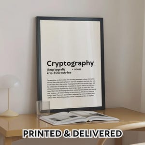 Op de afbeelding: Een zwart omlijste print met de definitie van "Cryptografie" in zwarte tekst op een witte achtergrond. De print staat op een lichtgekleurd bureau met een glas en een open boek. De tekst "PRINTED & DELIVERED" staat onderaan.