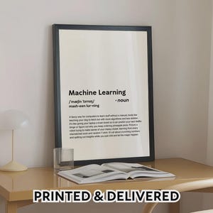 May include: A framed print with the words "Machine Learning" in black text. The print includes a definition and explanation of the term. The phrase "PRINTED & DELIVERED" is at the bottom. The print is on a desk with a glass and an open book.