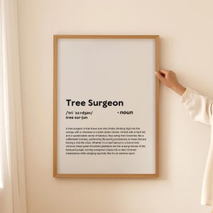 Op de afbeelding: Een ingelijste print met de woorden "Tree Surgeon" in vette zwarte tekst. De definitie van een boomchirurg staat onder de titel. De lijst is lichtbruin.
