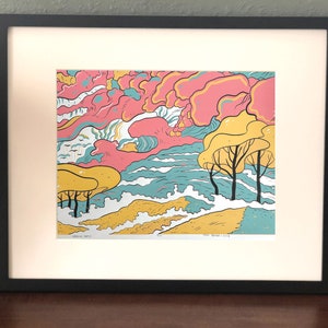 May include: Framed print of a colourful abstract landscape with pink, yellow, blue, and green hues. The print features stylised trees and clouds, creating a whimsical and modern aesthetic.
