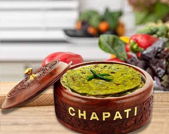 May include: A wooden chapati box with a carved design and the word "CHAPATI" in gold lettering. The box contains green chapatis and is partially open, with the lid resting beside it. A gold knob is on the lid.
