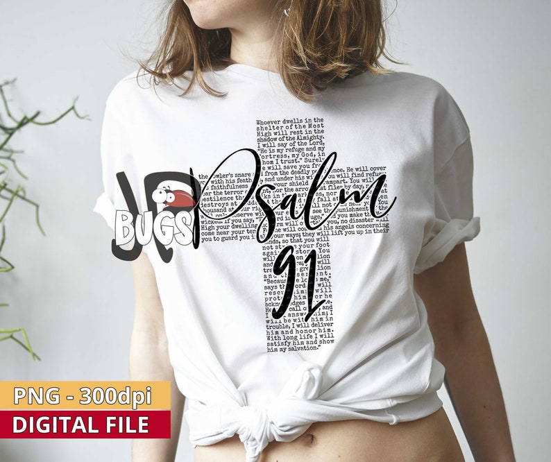 Pu&ograve; includere: Maglietta bianca con un design grafico in bianco e nero che presenta il testo "Salmo 91". Il testo &egrave; disposto in modo da creare una forma di croce. La grafica include anche una piccola illustrazione di un insetto rosso.