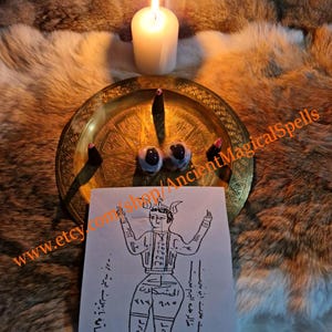 May include: A lit white candle, incense cones, and two dark-colored eye-shaped objects rest on a gold-colored plate. A black and white drawing of a figure with text is in the foreground. The background is a fur-like material.