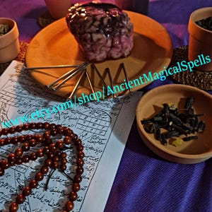 May include: A still life arrangement featuring a brain-shaped object on an orange plate, surrounded by ritualistic items. Includes a rosary, a bowl of herbs, candles, and a handwritten document. The text "AncientMagicalSpells" is visible.