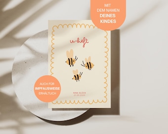 May include: A yellow card with a pink border and rounded corners. The card has a yellow and black bee illustration and the text "u-heft" in pink. The card also has the text "AUCH FÜR IMPFAUSWEISE ERHÄLTLICH" in a pink circle and the text "NINA GLÜCK 01.05.2023" in a pink rectangle. The card also has the text "MIT DEM NAMEN DEINES KINDES" in a pink rectangle at the top.