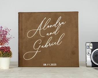 May include: A brown suede photo album with the names "Alondra and Gabriel" and the date "08.11.2025" printed in white cursive script.