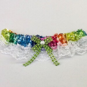 May include: A white lace garter with a rainbow sequined band and a green bow with a pearl in the center.