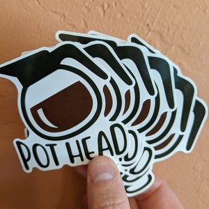 May include: A stack of black and white stickers with a coffee pot design and the text "POT HEAD".