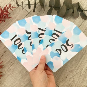 Könnte beinhalten: Ein Satz von fünf Aquarellkarten mit den Zahlen 100, 200, 300, 400 und 500 darauf gedruckt. Die Karten sind in Blautönen und Rosa.