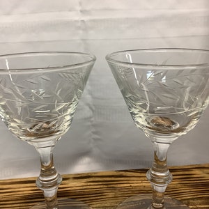 May include: Two clear, stemmed cocktail glasses with etched leaf designs. The glasses have a classic, elegant shape with a wide bowl and a slender stem. Perfect for serving cocktails or other beverages.