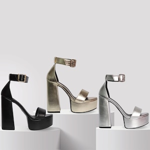 Könnte beinhalten: Drei Paar Plateausandalen in Schwarz, Gold und Silber. Jede Sandale hat einen dicken Plateauabsatz und einen Knöchelriemen.