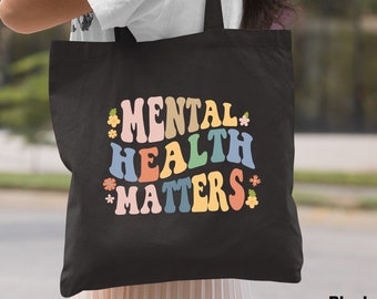 May include: Black tote bag with the text "MENTAL HEALTH MATTERS" in rainbow colors and small flower accents.