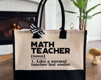 May include: A black and beige tote bag with the text "MATH TEACHER (noun) 1. Like a normal teacher but cooler" printed on it.