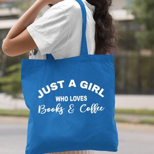 Puede incluir: Una bolsa de tela azul real con texto blanco que dice "Just a girl who loves books & coffee".