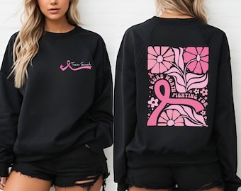 May include: Black sweatshirt with pink ribbon and text "Team Sarah" on the front. The back features a pink ribbon design with flowers and the words "A cure worth fighting for."