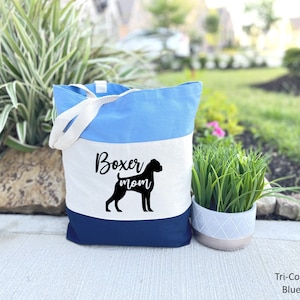 Puede incluir: Una bolsa de mano azul, blanca y azul marino con el texto "Boxer mom" y una silueta negra de un perro boxer.