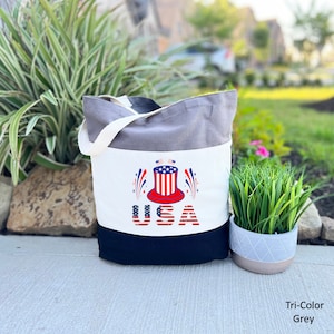 May include: A grey, white, and black canvas tote bag with a red, white, and blue Uncle Sam hat graphic and the word "USA" in red, white, and blue.