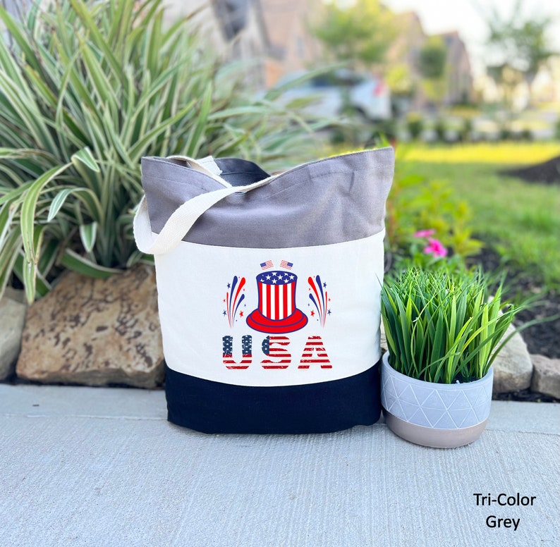 May include: A grey, white, and black canvas tote bag with a red, white, and blue Uncle Sam hat graphic and the word "USA" in red, white, and blue.