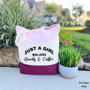 Puede incluir: Una bolsa de mano tricolor con un dise&ntilde;o rosa, blanco y burdeos. La bolsa tiene un panel de lona blanco con el texto "Just a girl who loves books & coffee".