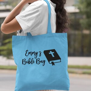 May include: Light blue tote bag with the text "Emmy's Bible Bag" and a black silhouette of a closed book with a cross on the cover.