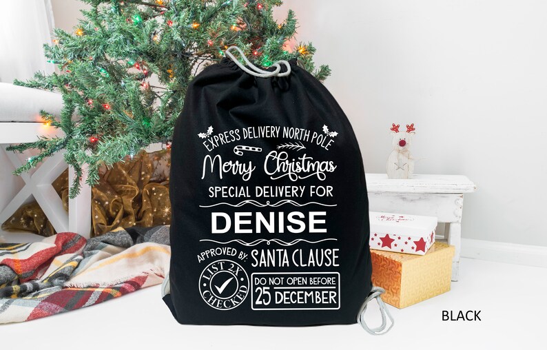 May include: Black Christmas gift bag with white text that reads "Express Delivery North Pole Merry Christmas Special Delivery for Denise Approved by: Santa Clause List 2x Checked Do Not Open Before 25 December".